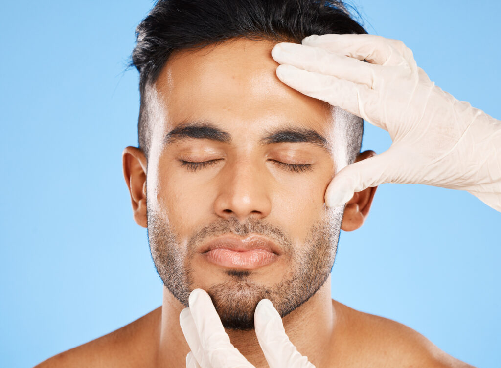 man's face with hands examining his skin