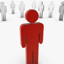 Red cutout figure of a person standing away from a group of white figure cutouts.