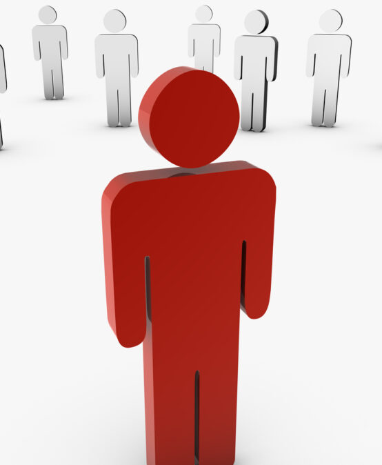 Red cutout figure of a person standing away from a group of white figure cutouts.